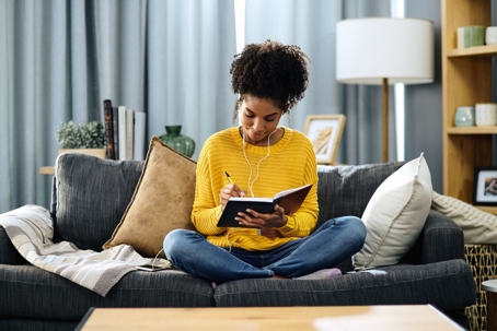 woman on couch writing in journal